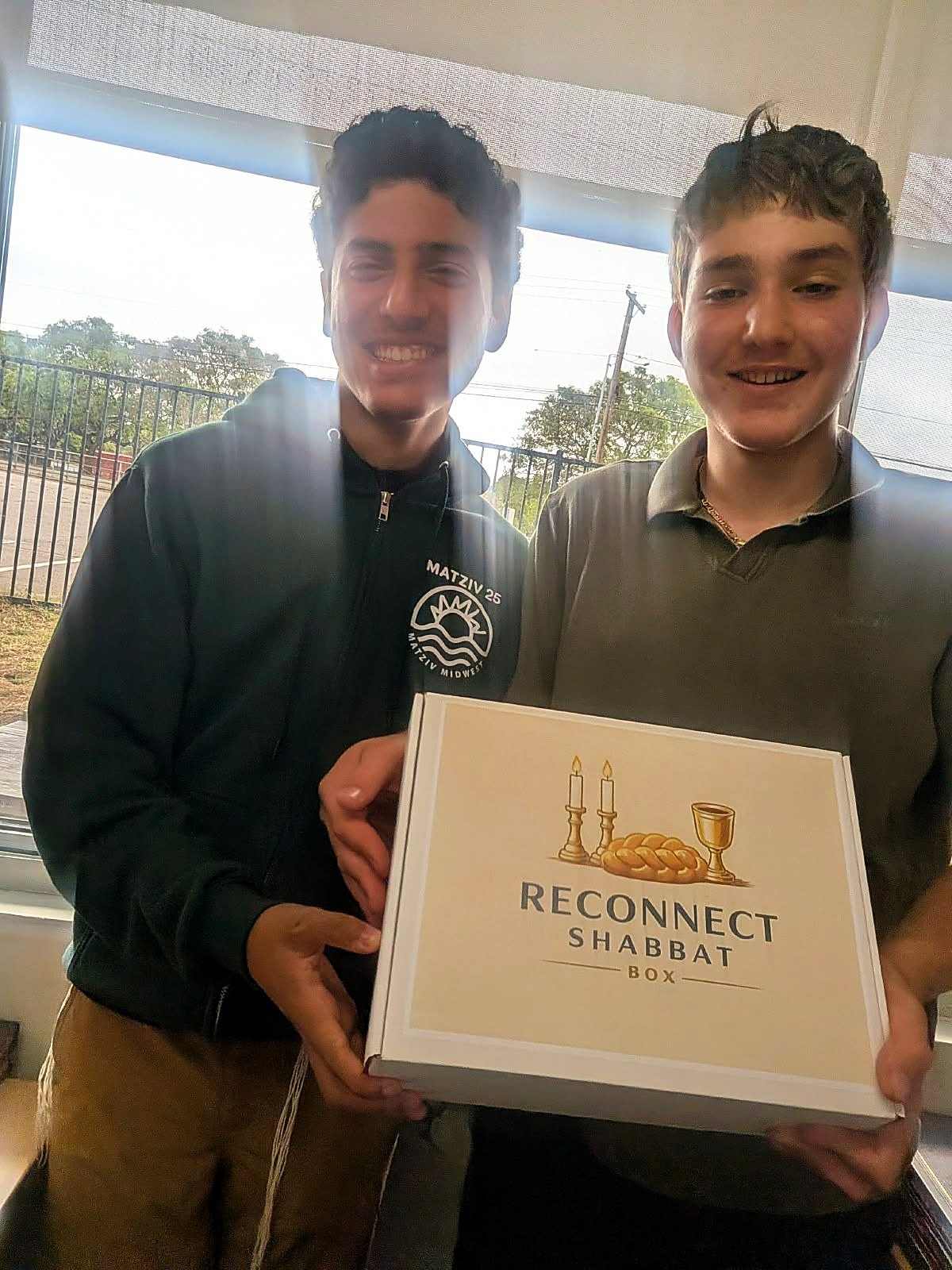 Asher and Isaac smiling and holding a ReConnect Shabbat Box